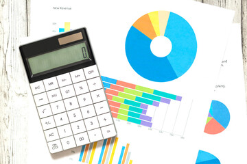 White calculator on paper table with diagram on a white background. Business concept.