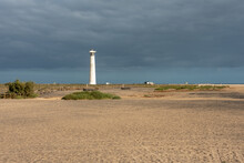 Beach And Lighthouse Under Cloudy Sky. Morro Jable, Jandia Peninsula, Fuerteventura, Canary Islands. 