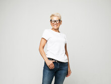 Aged People, Lifestyle And Maturity Concept: Blonde Fifty Year Old European Female With Stylish Pixie Haircut And Eyeglasses Smiling At Camera And Posing Isolated Over Grey Background.