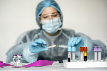 Wall Mural - Scientist wearing highly protective clothes holding a tube showing positive Covid test result