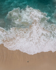 Sticker - Vertical top view of foamy ocean waves washing the sandy coast