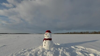 Wall Mural - Funny snowman in stylish red hat and red scalf on snowy field during snowing. Winter holiday and Christmas background. UHD 4k time lapse video