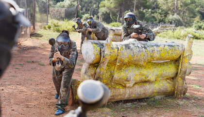 Poster - Paintball players aiming and shooting with the marker guns at the opposing team outdoors