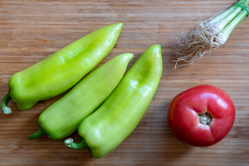 Canvas Print - Top view closeup of green bell peppers, tomato, spring onions on a wooden table