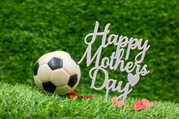 Soccer ball for Mother's Day on green grass background with love 