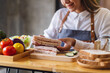 Closeup image of a beautiful female chef cooking a whole wheat ham cheese sandwich in kitchen