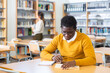 Adult male student working in library, reading and writing notes, concept of adult education