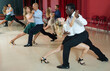 © JackF - Smiling adult pairs dancing tango movements in modern dance studio
