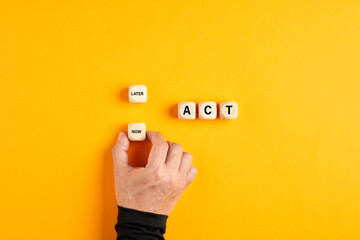 the word act on wooden blocks with a male hand choosing the now option. taking action