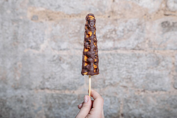 Wall Mural - Vertical shot of a person holding a lollipop-shaped belgian waffle with chocolate