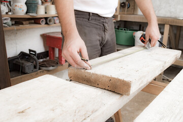 Male carpenter working with wood material in a garage.