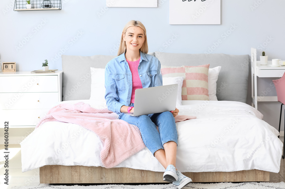 Young beautiful woman with laptop in bedroom
