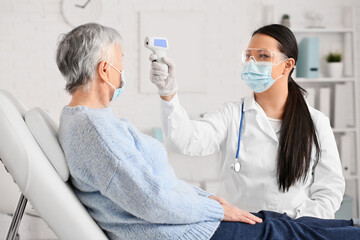 Poster - Doctor measuring temperature of senior woman in clinic