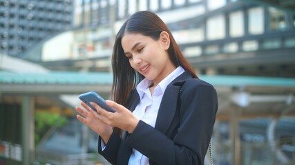 A young business woman wearing black suit is using smart phone , in the city, Business Lifestyle Concept..