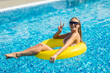© F8  \ Suport Ukraine - Young woman with perfect sexy body in bikini and glamorous sunglasses, posing on an inflatable yellow ring in the swimming pool outdoors