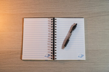 Wall Mural - High angle shot of an open blank notepad with a black pen on a wooden desk