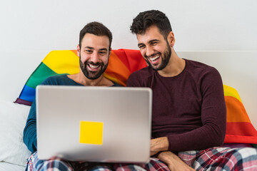 Happy gay men couple using laptop in bed - Homosexual love and gender equality in relationship concept