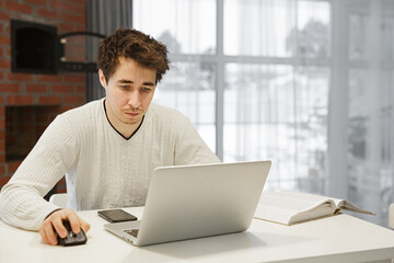 Wall Mural - A man working on a laptop at home at bright kitchen