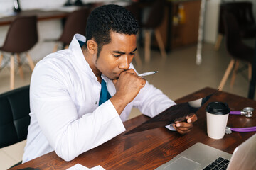 Poster - Close-up portrait of African American black man doctor is analyzing history disease of patient using MRI brain head scan image while working at laptop. Concept of medicine and health care.