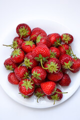 Canvas Print - Strawberries on white plate. Freshly picked strawberry. Organic berries on white background. Village garden harvest.