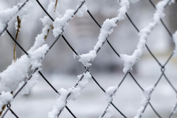 Closeup shot of a metal net fence covered in snow