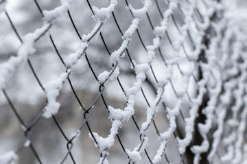 Closeup shot of a metal net fence covered in snow