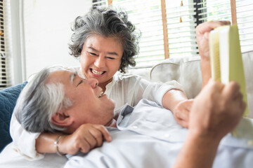 Happy Asian senior couple in love hugging and laughing enjoying life and spending time together at home