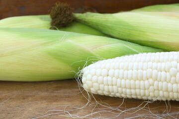 Wall Mural - Close up raw white corn (peeled can see inside) on brown wood table background