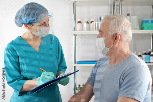 Female medical professional interviewing a senior adult man. Hospital healthcare case.