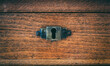 Secret, mystery concept. Close up view of keyhole on wooden background