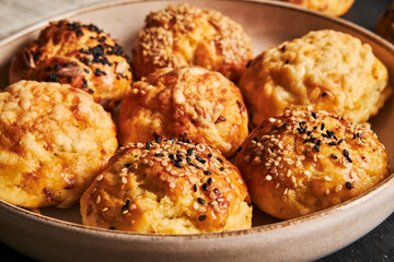 Closeup of a plate full of delicious cheese balls with sesame seeds on a black surface