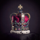 Fototapeta Londyn - Royal golden crown with jewels on pillow on black background. Symbols of UK United Kingdom monarchy.