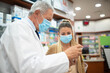 © Minerva Studio - Pharmacist suggesting a product to a customer while wearing a coronavirus mask
