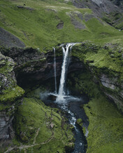 Breathtaking View Of A Powerful Waterfall Surrounded By Rocky Cliffs In Iceland