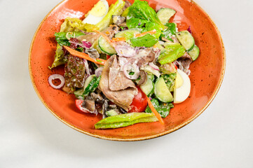 Vegetable vegetarian salad with tomatoes, peppers and onions on white table.