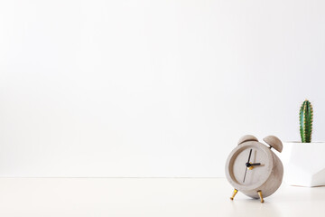 Wall Mural - A desk against a white wall. Copy space. Cactus in a geometric pot. Concrete clock.