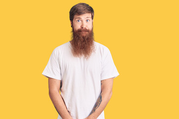 Canvas Print - Handsome young red head man with long beard wearing casual white tshirt puffing cheeks with funny face. mouth inflated with air, crazy expression.