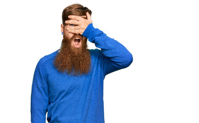 Canvas Print - Young irish redhead man wearing casual clothes peeking in shock covering face and eyes with hand, looking through fingers with embarrassed expression.