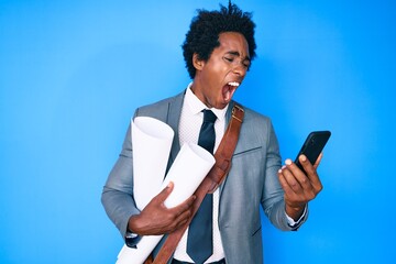 Poster - Handsome african american man with afro hair holding paper blueprints using smartphone angry and mad screaming frustrated and furious, shouting with anger. rage and aggressive concept.