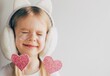 Studio photo of a lovely little girl with paper hearts. Valentines day. Portrait of a child holding pink valentine. Space for text. Funny face.