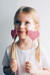 Lovely little girl with paper hearts. Valentines day. Portrait of a child holding pink valentine.