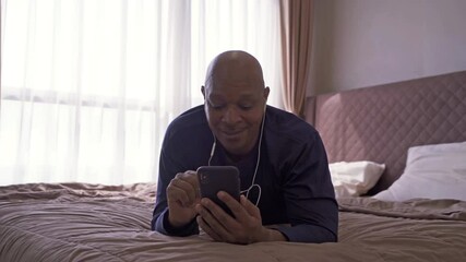 Wall Mural - Happy smiling business, black man, African American people talking on the phone to colleagues in webcam video call conference in quarantine on bed in bedroom at home in morning. Lifestyle