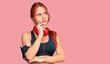 © Krakenimages.com - Young redhead woman wearing gym clothes and using headphones serious face thinking about question with hand on chin, thoughtful about confusing idea