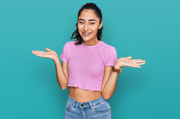 Hispanic teenager girl with dental braces wearing casual clothes smiling showing both hands open palms, presenting and advertising comparison and balance