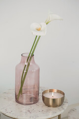 Poster - Vertical shot of a beautiful vase with white flowers and a burning candle on the table