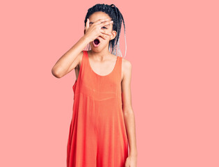 Poster - Cute african american girl wearing casual clothes peeking in shock covering face and eyes with hand, looking through fingers with embarrassed expression.