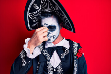 Canvas Print - Young man wearing mexican day of the dead costume over red tired rubbing nose and eyes feeling fatigue and headache. stress and frustration concept.