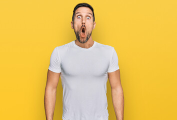 Poster - Handsome man with beard wearing casual white t shirt afraid and shocked with surprise expression, fear and excited face.