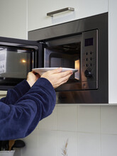 Vertical Shot Of A Male Putting A Plate In The Microwave