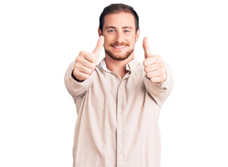 Young handsome caucasian man wearing casual clothes approving doing positive gesture with hand, thumbs up smiling and happy for success. winner gesture.